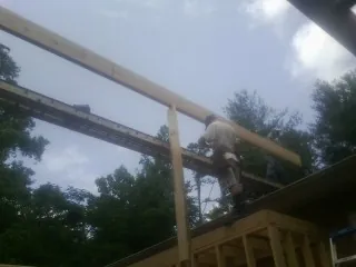 Carpenter setting a ridge beam over a new addition frame — Ice Dam Removal by Roofing Brothers in Amber