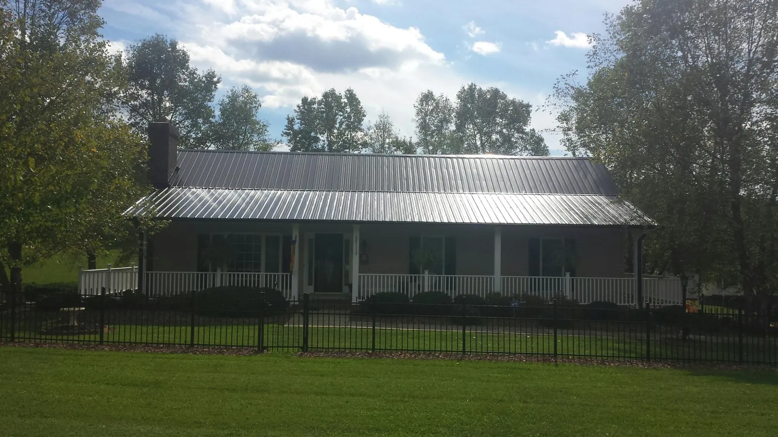 Gray metal roof on a brick ranch with a full width front porch — Gutter Guard Installation work by our crew in Amber