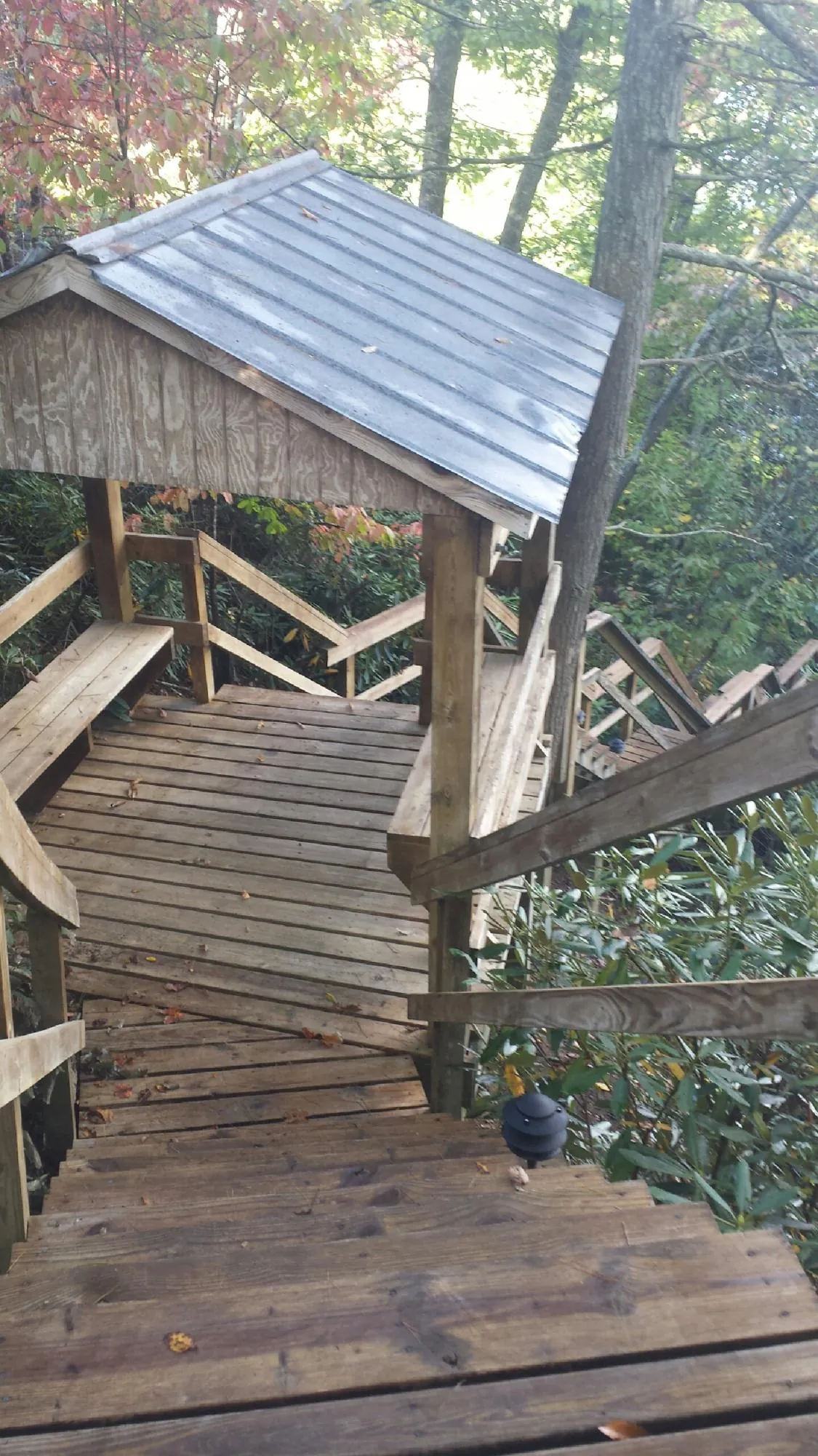 Metal roofed shelter over wooden steps on a wooded walkway — Skylight Repair & Installation work by our crew in Amber