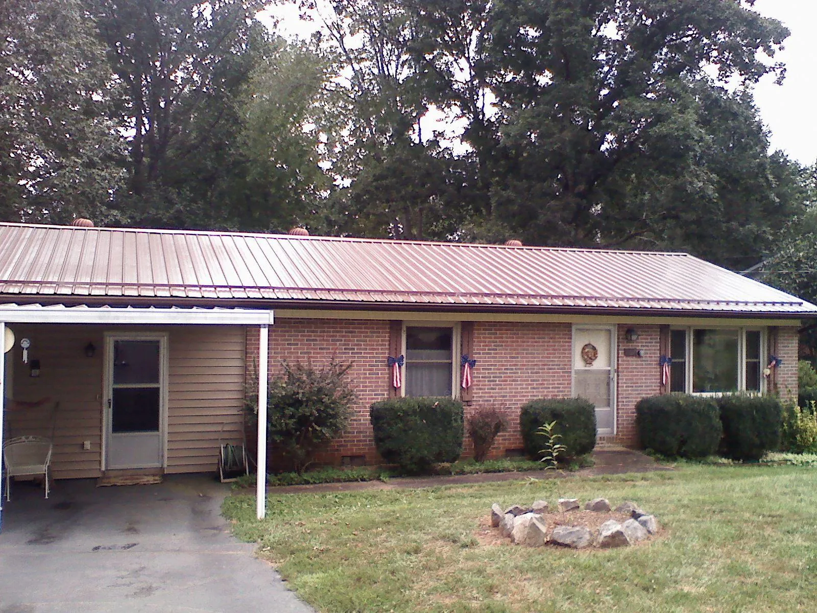 Bronze metal roof and carport on a brick ranch home — Roof Repair work by our crew in Amber