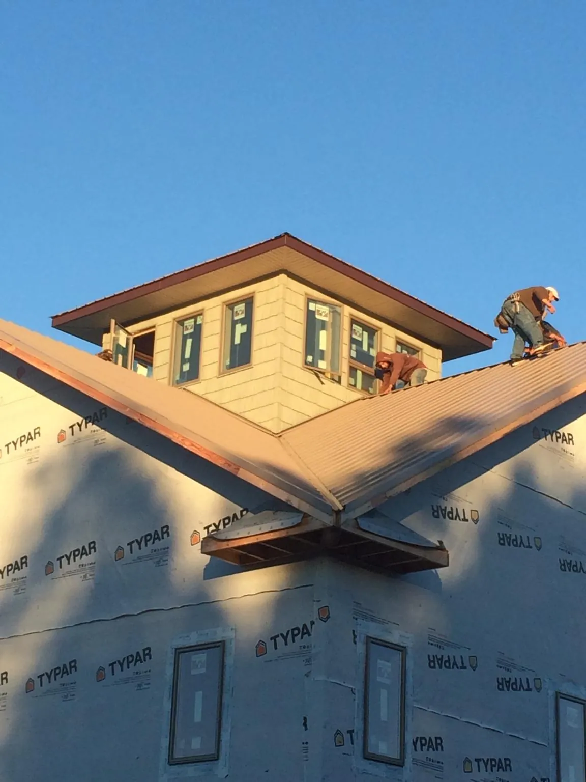 Roofers working around a rooftop cupola on a new metal roof at sunset — Roof Waterproofing in Amber by Roofing Brothers